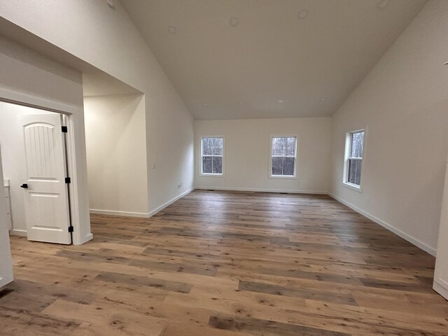 spare room featuring high vaulted ceiling and hardwood / wood-style floors