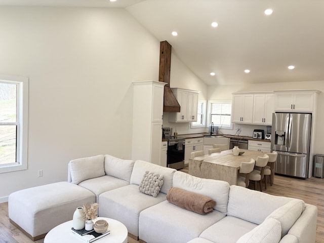 living room featuring high vaulted ceiling, recessed lighting, and light wood-style flooring