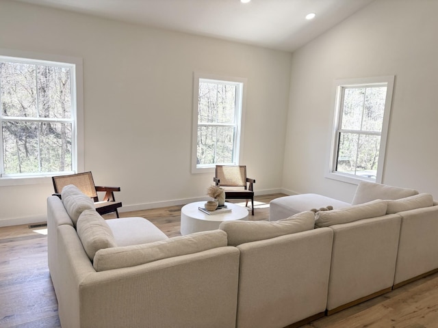 living area featuring a wealth of natural light, light wood finished floors, recessed lighting, and lofted ceiling