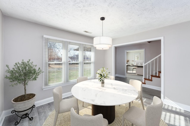 dining area with a textured ceiling and hardwood / wood-style floors