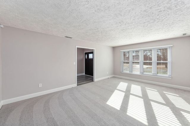 carpeted spare room with a textured ceiling