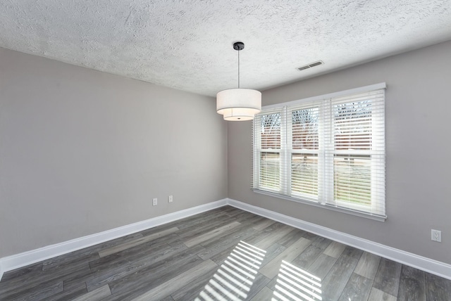 empty room featuring a textured ceiling and dark hardwood / wood-style flooring