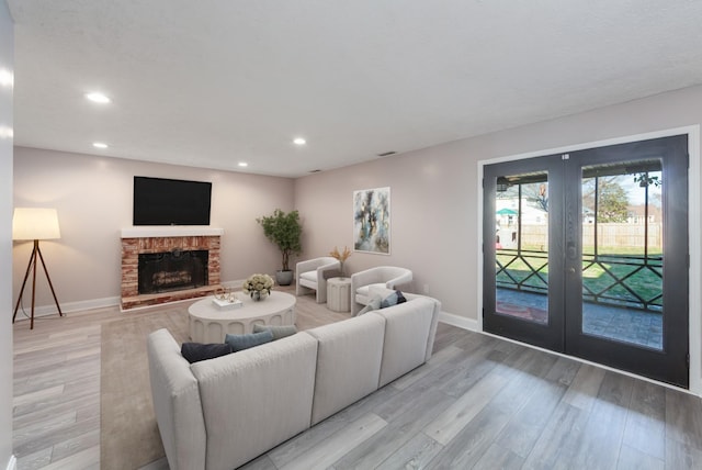 living room featuring french doors, a brick fireplace, and light hardwood / wood-style flooring