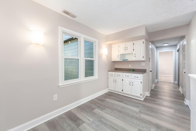 kitchen featuring white cabinetry, a textured ceiling, and light hardwood / wood-style flooring