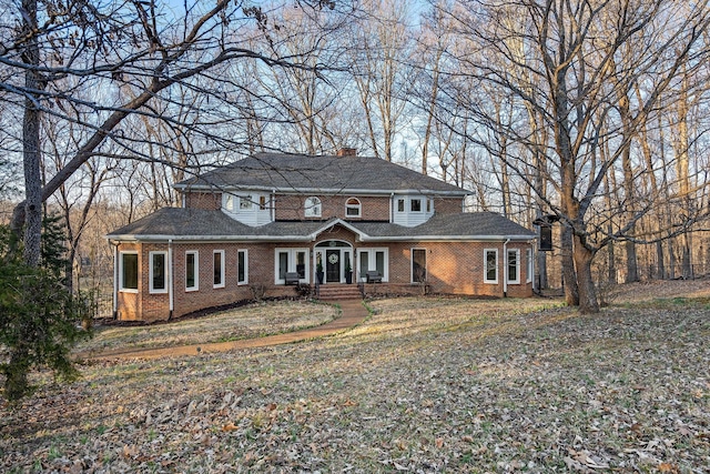 view of front of property featuring a chimney and brick siding