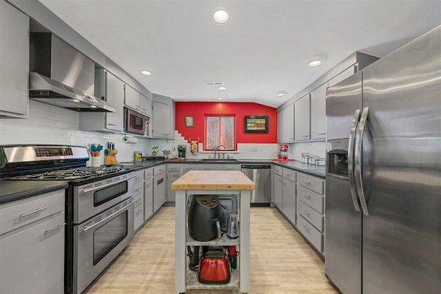 kitchen featuring butcher block countertops, light hardwood / wood-style flooring, sink, appliances with stainless steel finishes, and wall chimney exhaust hood