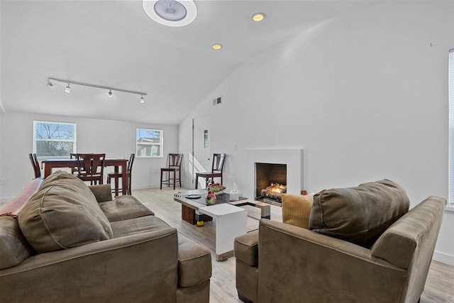 living room featuring light hardwood / wood-style floors, high vaulted ceiling, and rail lighting