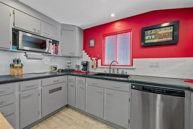 kitchen featuring stainless steel appliances, light hardwood / wood-style floors, sink, backsplash, and gray cabinets