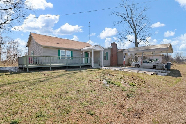 rear view of property featuring a yard, a wooden deck, and a carport