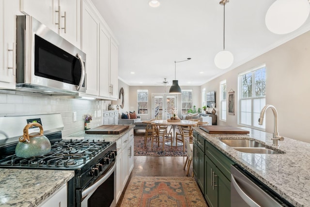 kitchen with appliances with stainless steel finishes, sink, pendant lighting, and white cabinets