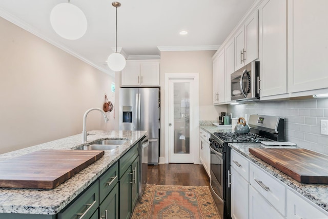 kitchen featuring stainless steel appliances, an island with sink, white cabinets, pendant lighting, and sink