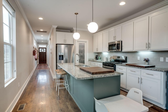 kitchen featuring sink, decorative light fixtures, stainless steel appliances, white cabinets, and ornamental molding