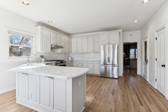 kitchen with kitchen peninsula, appliances with stainless steel finishes, white cabinets, and backsplash