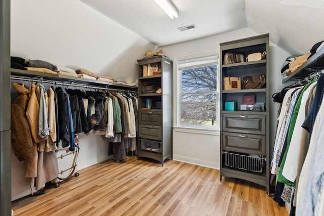 spacious closet with light hardwood / wood-style floors and vaulted ceiling