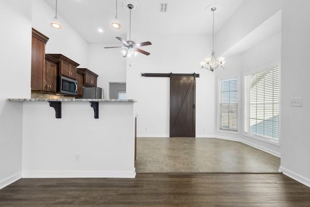 kitchen with kitchen peninsula, a barn door, decorative light fixtures, appliances with stainless steel finishes, and a breakfast bar area