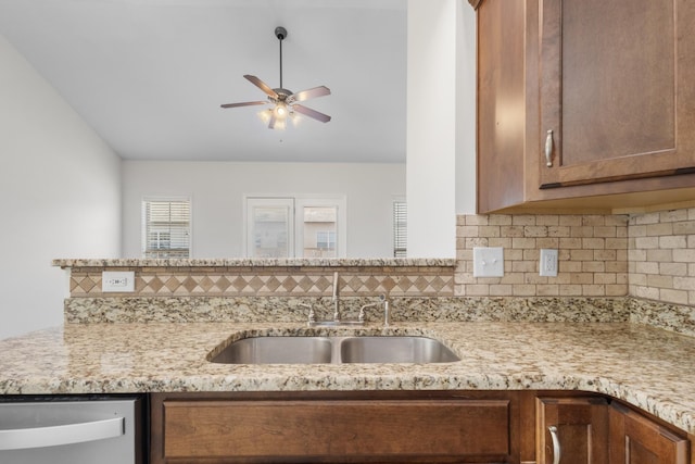 kitchen with light stone counters, stainless steel dishwasher, decorative backsplash, ceiling fan, and sink