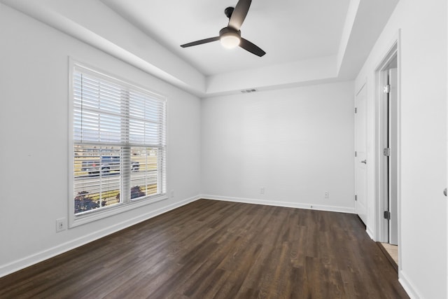 unfurnished bedroom featuring ceiling fan, a tray ceiling, and dark hardwood / wood-style floors