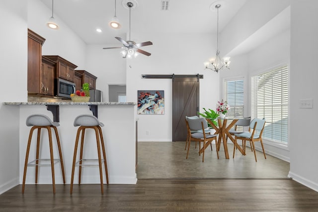 kitchen featuring a kitchen breakfast bar, pendant lighting, a barn door, dark hardwood / wood-style floors, and kitchen peninsula