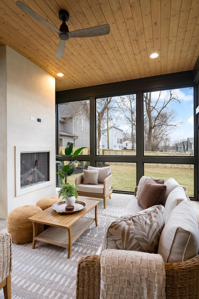 sunroom with wooden ceiling, exterior fireplace, and ceiling fan