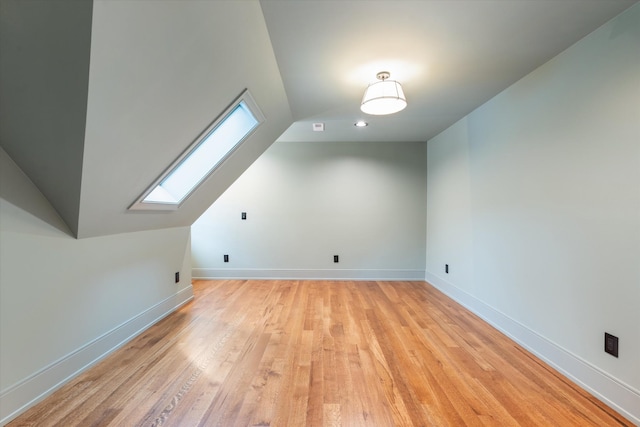 additional living space with light hardwood / wood-style floors and vaulted ceiling with skylight