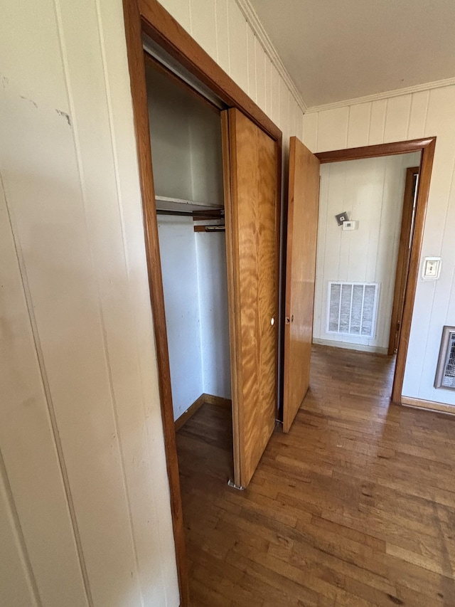 hall featuring heating unit, wood finished floors, visible vents, and crown molding