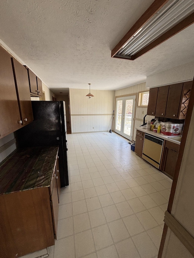 kitchen with a textured ceiling, dishwashing machine, dark brown cabinets, french doors, and freestanding refrigerator