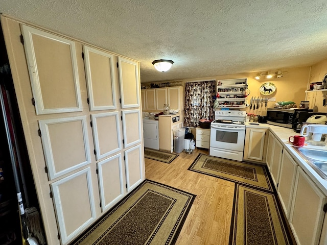 kitchen with washer and dryer, light hardwood / wood-style floors, a textured ceiling, and white electric range