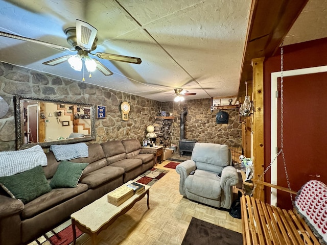 living room featuring ceiling fan, parquet flooring, and a wood stove