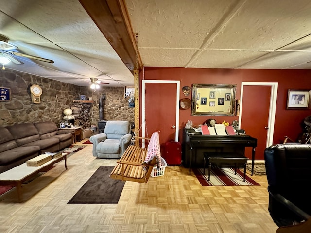 living room featuring a wood stove, ceiling fan, and light parquet flooring