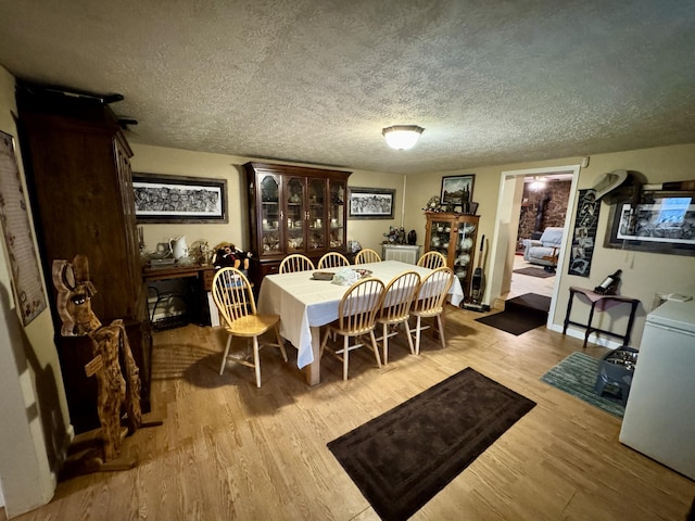 dining room with a textured ceiling and light hardwood / wood-style floors