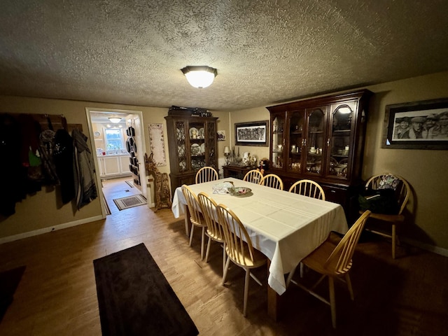 dining area with light hardwood / wood-style flooring and a textured ceiling