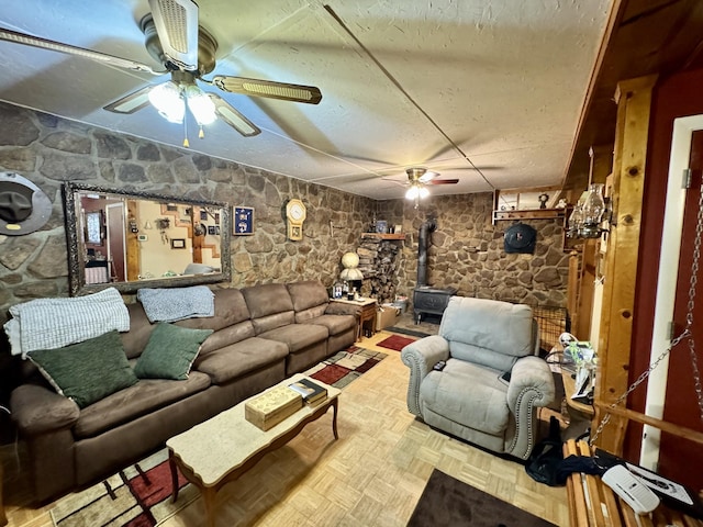 living room with ceiling fan, parquet flooring, and a wood stove