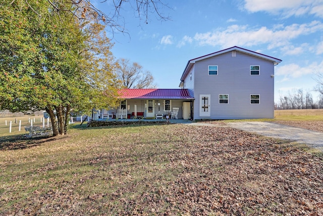 rear view of house with covered porch and a lawn