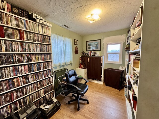 office space with a textured ceiling and light hardwood / wood-style flooring