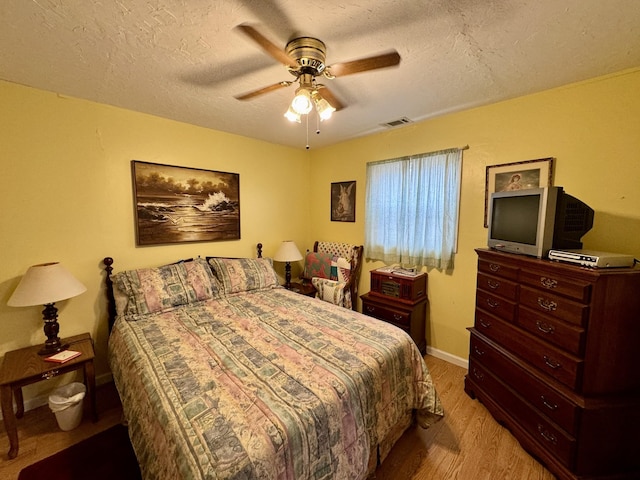 bedroom with light hardwood / wood-style flooring, ceiling fan, and a textured ceiling