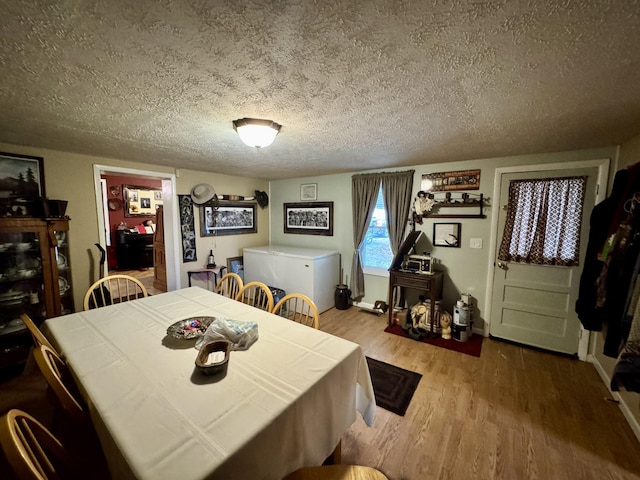 dining space featuring wood-type flooring and a textured ceiling