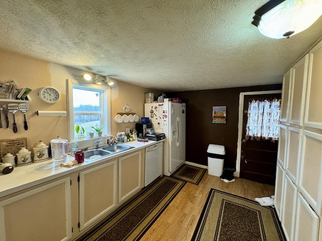 kitchen featuring sink, white appliances, a textured ceiling, and light hardwood / wood-style floors