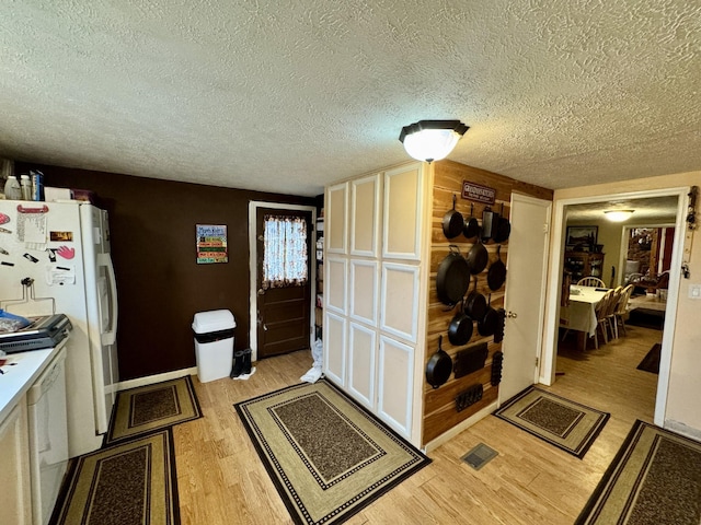 kitchen featuring light wood-type flooring, white fridge, and a textured ceiling