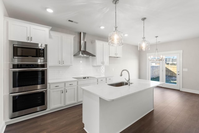 kitchen featuring sink, wall chimney exhaust hood, white cabinetry, and a kitchen island with sink