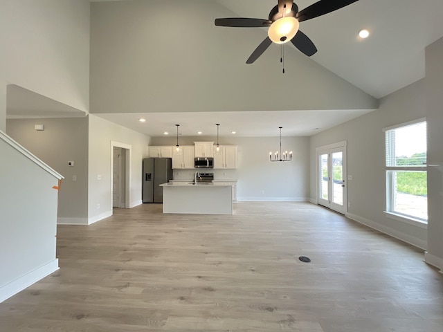 unfurnished living room featuring recessed lighting, baseboards, light wood-style floors, high vaulted ceiling, and ceiling fan with notable chandelier