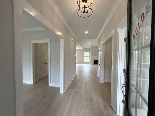 hallway featuring ornamental molding, light wood-type flooring, baseboards, and recessed lighting