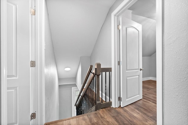 stairs featuring wood-type flooring and lofted ceiling