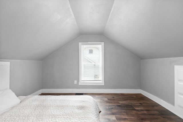 bedroom with vaulted ceiling and dark hardwood / wood-style floors