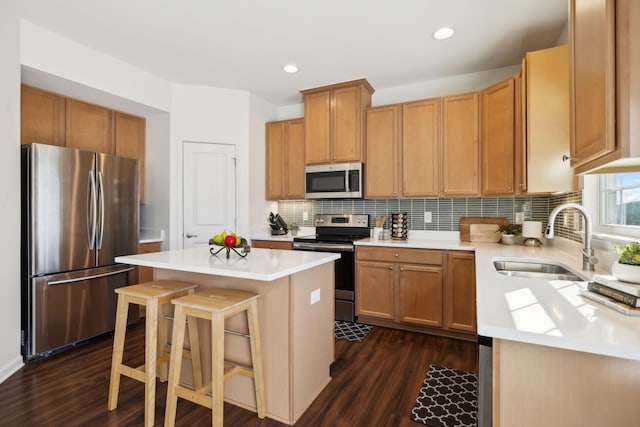 kitchen with appliances with stainless steel finishes, decorative backsplash, a breakfast bar, a center island, and sink