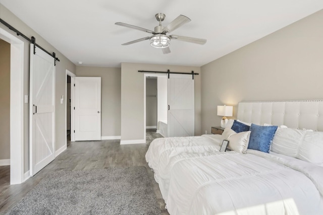 bedroom featuring hardwood / wood-style floors, ceiling fan, and a barn door