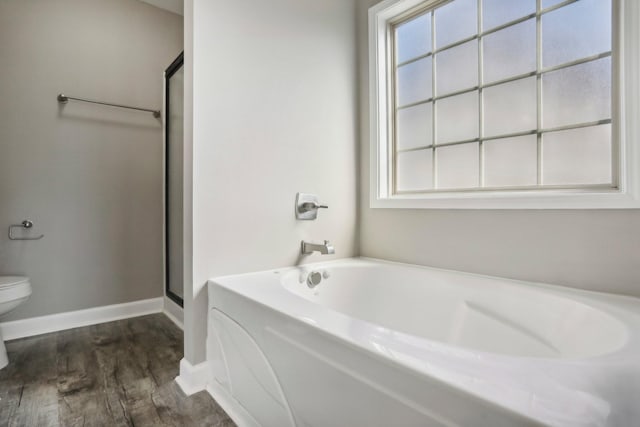 bathroom with wood-type flooring, plus walk in shower, plenty of natural light, and toilet