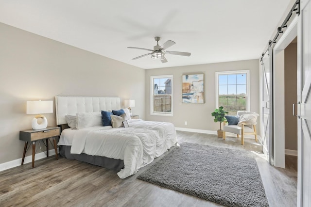 bedroom featuring hardwood / wood-style flooring, ceiling fan, and a barn door