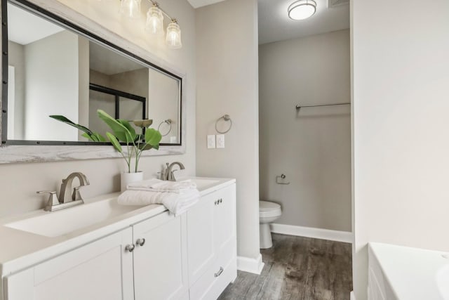 bathroom with toilet, vanity, and wood-type flooring