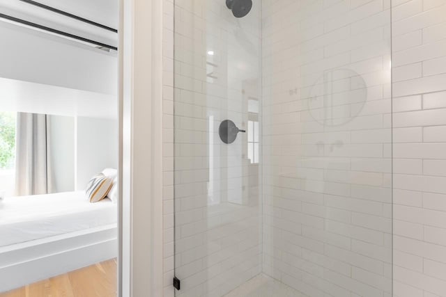 bathroom with wood-type flooring and a tile shower