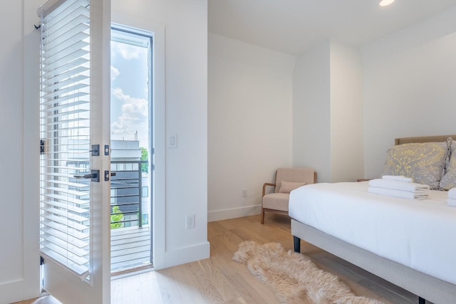 bedroom featuring multiple windows, light wood-type flooring, and access to outside